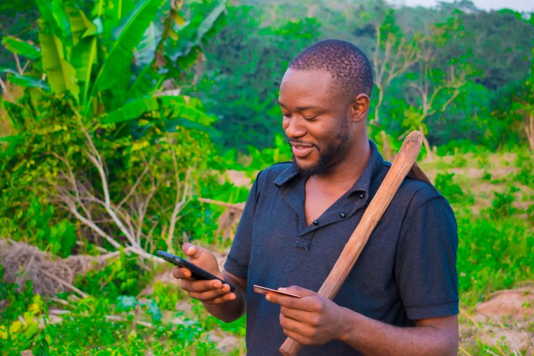 Young African farmer making an online payment with his debit card on his phone.